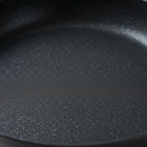 Macro view of a non-stick pan's surface, highlighted with infused diamond particles for enhanced durability.